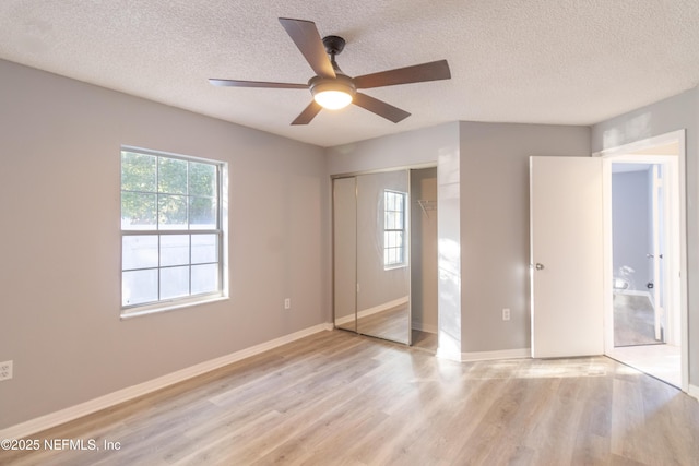 unfurnished bedroom featuring ceiling fan, a closet, light hardwood / wood-style floors, and a textured ceiling