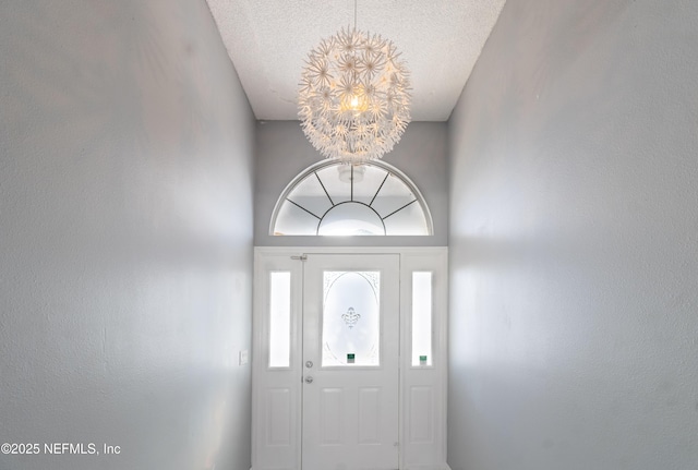 entrance foyer with a chandelier, a towering ceiling, and a textured ceiling