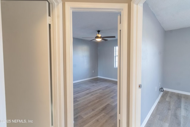 hall with light hardwood / wood-style floors and a textured ceiling