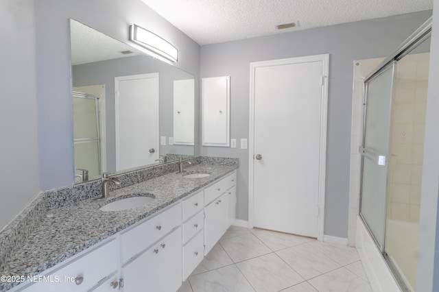 bathroom featuring shower / bath combination with glass door, vanity, a textured ceiling, and tile patterned flooring