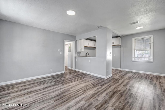 unfurnished living room featuring hardwood / wood-style floors, a textured ceiling, and sink