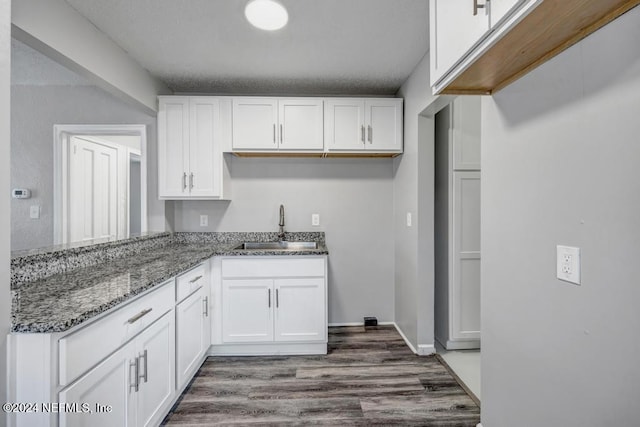 kitchen with stone counters, white cabinetry, sink, and dark hardwood / wood-style floors