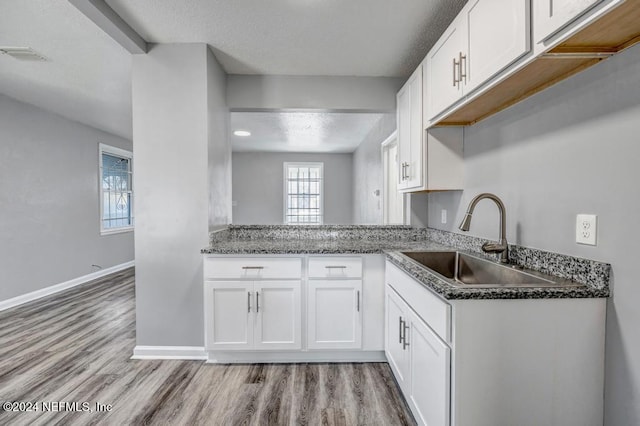 kitchen with white cabinets, light hardwood / wood-style floors, sink, and a textured ceiling