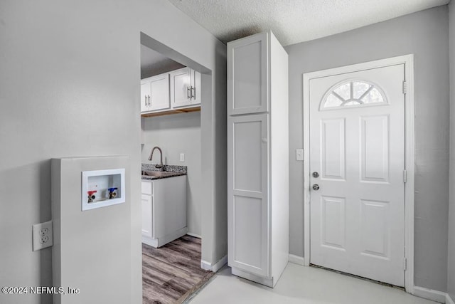 kitchen featuring sink, white cabinets, a textured ceiling, and light wood-type flooring