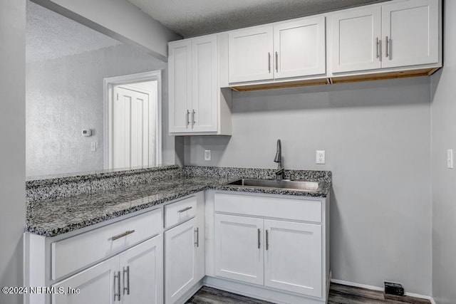 kitchen featuring a textured ceiling, dark hardwood / wood-style floors, white cabinetry, and sink