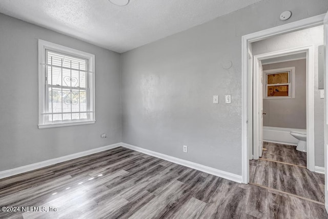 unfurnished room with a textured ceiling and dark hardwood / wood-style floors