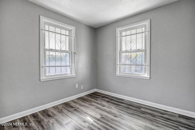 spare room with a textured ceiling and dark hardwood / wood-style flooring