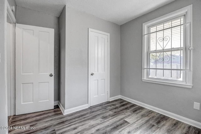 unfurnished bedroom with wood-type flooring and a textured ceiling