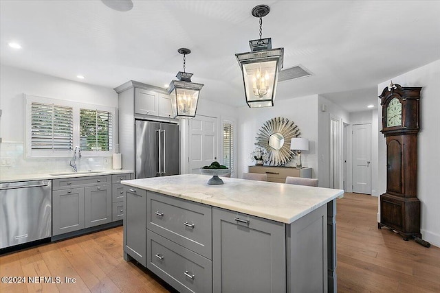 kitchen featuring light hardwood / wood-style flooring, stainless steel appliances, sink, gray cabinets, and decorative light fixtures