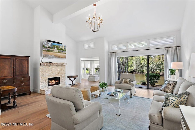 living room featuring a stone fireplace, beam ceiling, light hardwood / wood-style flooring, a chandelier, and high vaulted ceiling