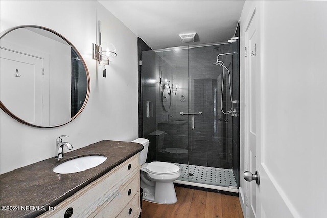 bathroom featuring vanity, hardwood / wood-style floors, a shower with shower door, and toilet