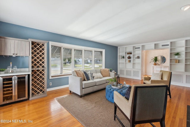 living room with built in features, bar, wine cooler, and light hardwood / wood-style flooring