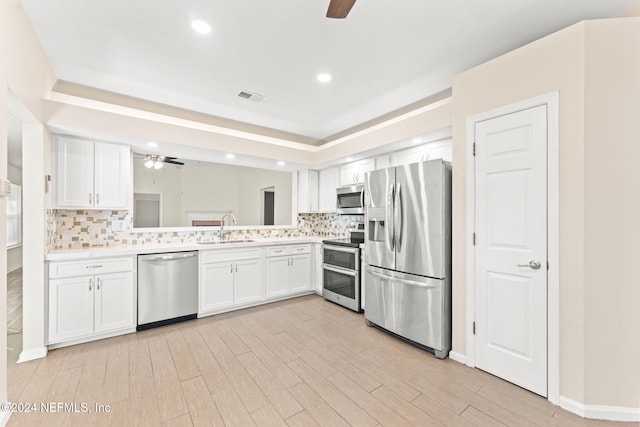 kitchen featuring decorative backsplash, appliances with stainless steel finishes, white cabinetry, light hardwood / wood-style floors, and sink