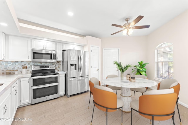 kitchen featuring light hardwood / wood-style flooring, stainless steel appliances, tasteful backsplash, white cabinetry, and ceiling fan