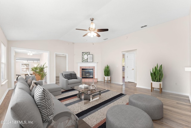 living room with lofted ceiling, a tiled fireplace, and dark wood-type flooring