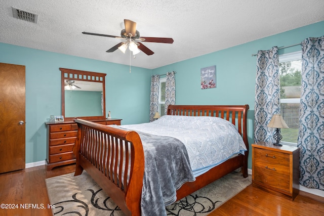 bedroom with ceiling fan, hardwood / wood-style flooring, and a textured ceiling