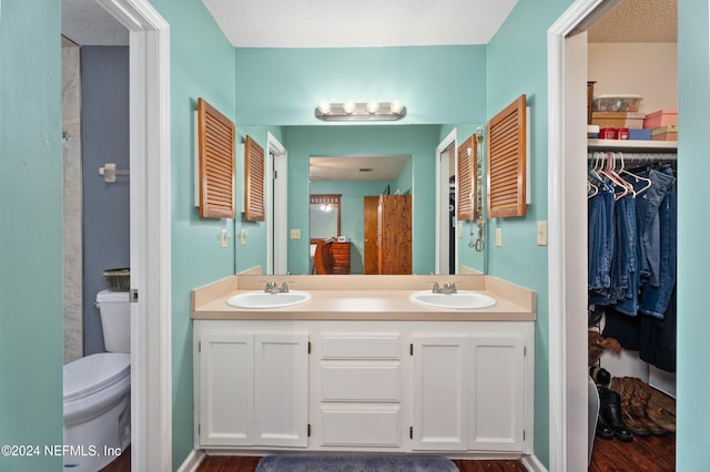 bathroom with toilet, hardwood / wood-style floors, vanity, and a textured ceiling