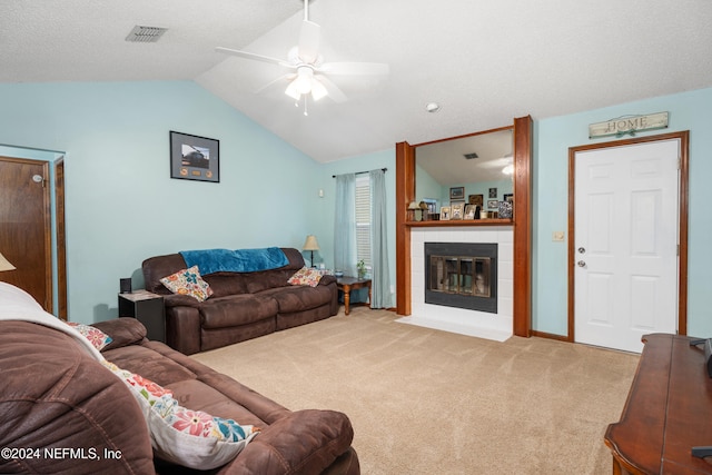 living room featuring lofted ceiling, carpet floors, a tile fireplace, and ceiling fan