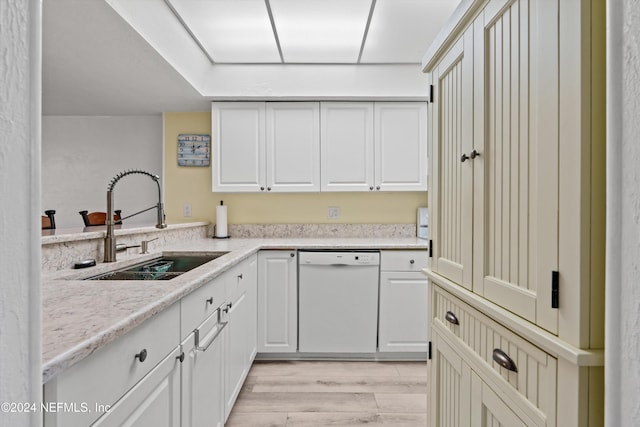 kitchen featuring white cabinetry, sink, white dishwasher, light stone countertops, and light wood-type flooring