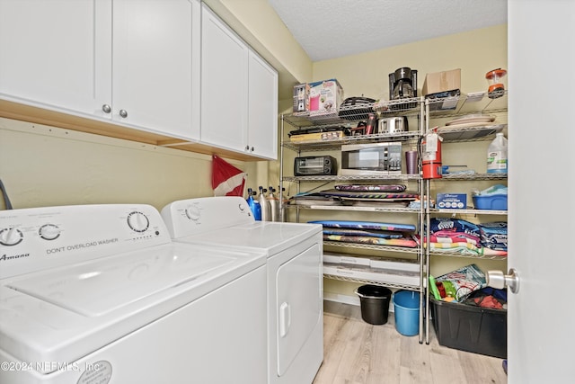 washroom with cabinets, separate washer and dryer, a textured ceiling, and light wood-type flooring