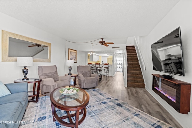 living room with a textured ceiling, ceiling fan with notable chandelier, and hardwood / wood-style flooring