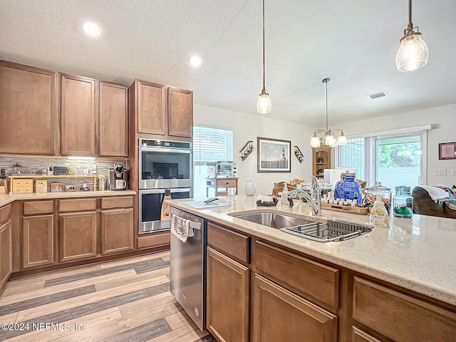 kitchen with sink, appliances with stainless steel finishes, light hardwood / wood-style flooring, and hanging light fixtures