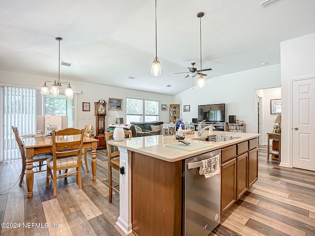 kitchen featuring lofted ceiling, dishwasher, a kitchen island with sink, decorative light fixtures, and light wood-type flooring