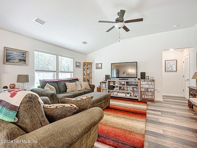 living room with ceiling fan, vaulted ceiling, and light wood-type flooring