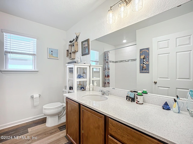 bathroom with toilet, hardwood / wood-style floors, walk in shower, and vanity