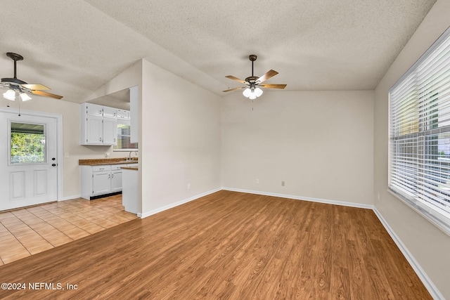 unfurnished living room with light hardwood / wood-style floors, a textured ceiling, and ceiling fan