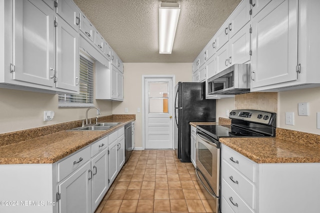 kitchen with light tile patterned flooring, white cabinetry, stainless steel appliances, and sink