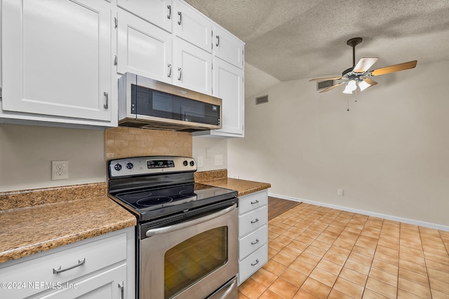 kitchen featuring vaulted ceiling, white cabinets, stainless steel appliances, and light tile patterned flooring