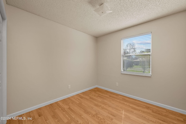 spare room with a textured ceiling and light wood-type flooring