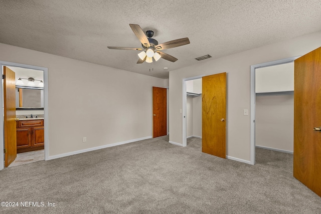 unfurnished bedroom featuring connected bathroom, a walk in closet, and ceiling fan