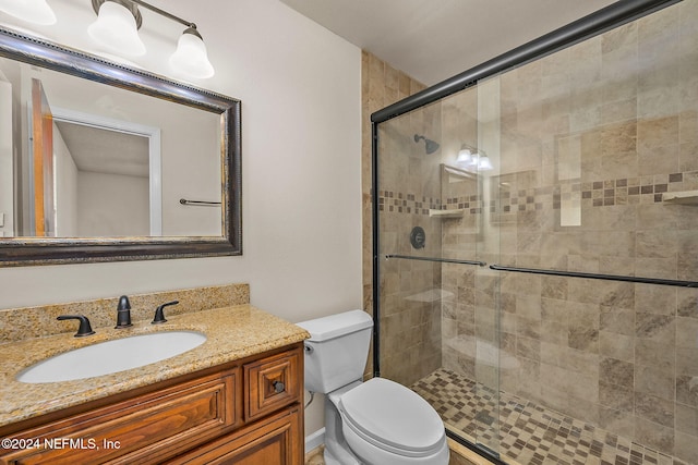 bathroom with vanity, toilet, and a shower with shower door