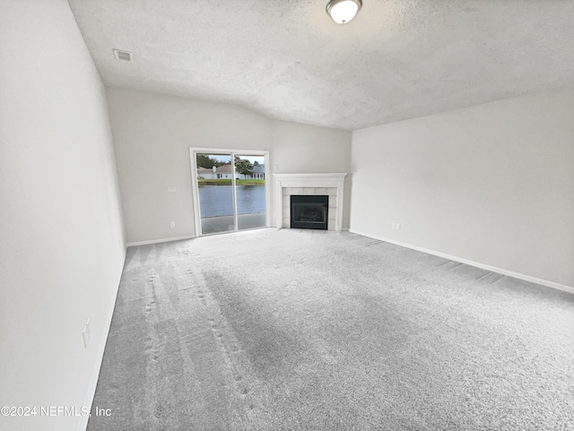 unfurnished living room featuring a textured ceiling, a fireplace, and carpet flooring