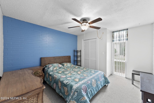 carpeted bedroom featuring access to outside, a closet, brick wall, a textured ceiling, and ceiling fan