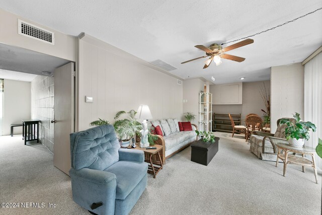 carpeted living room with ceiling fan and a textured ceiling