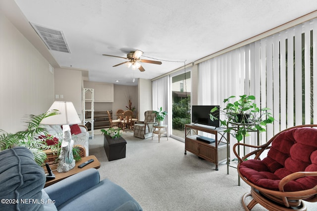 carpeted living room with ceiling fan and a textured ceiling