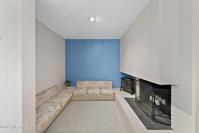 carpeted living room with a textured ceiling and a wood stove