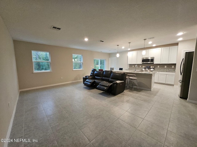 living room with light tile patterned floors, a textured ceiling, and sink