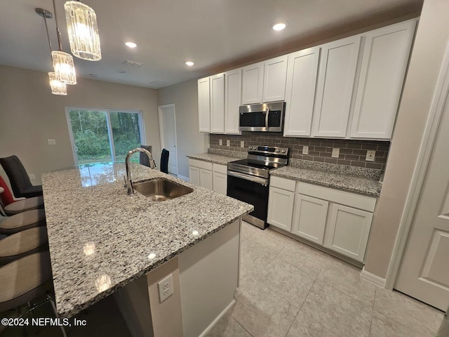 kitchen with a kitchen island with sink, white cabinetry, sink, and appliances with stainless steel finishes