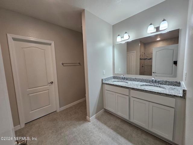 bathroom with tile patterned flooring, vanity, and tiled shower