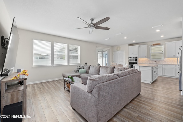 living room with light wood-type flooring, sink, and ceiling fan