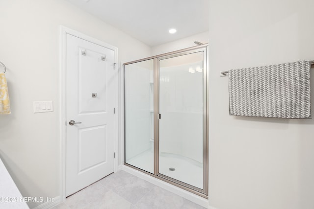 bathroom with a shower with shower door and tile patterned floors