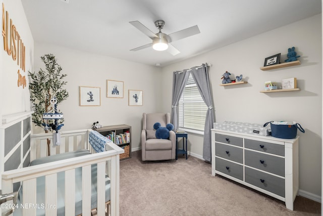 bedroom featuring light colored carpet, ceiling fan, and a crib