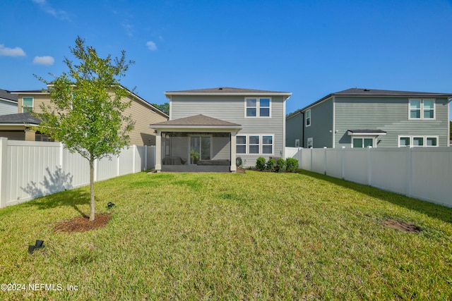 back of property with a sunroom and a yard