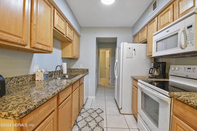 kitchen with light tile patterned floors, sink, white appliances, and dark stone counters