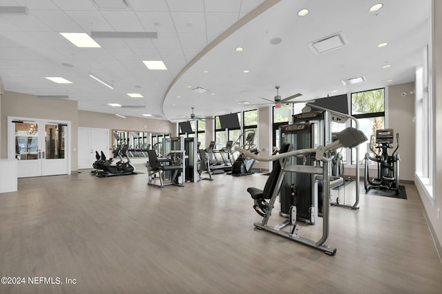 exercise room featuring wood-type flooring, ceiling fan, a wall of windows, and french doors