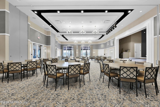 dining area with an inviting chandelier, a towering ceiling, and a tray ceiling